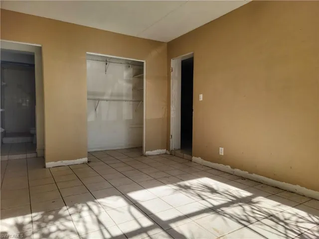 Unfurnished bedroom with light tile patterned floors, a closet, and baseboards