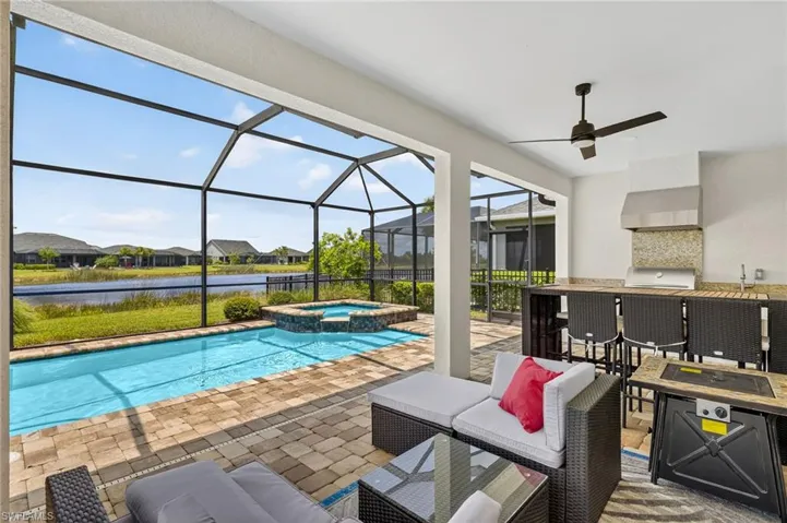 View of pool with exterior bar, a water view, a lanai, and a patio area