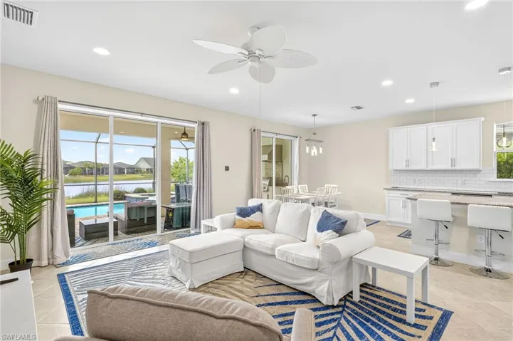 Living area featuring a ceiling fan, light tile patterned floors, recessed lighting, and a water view