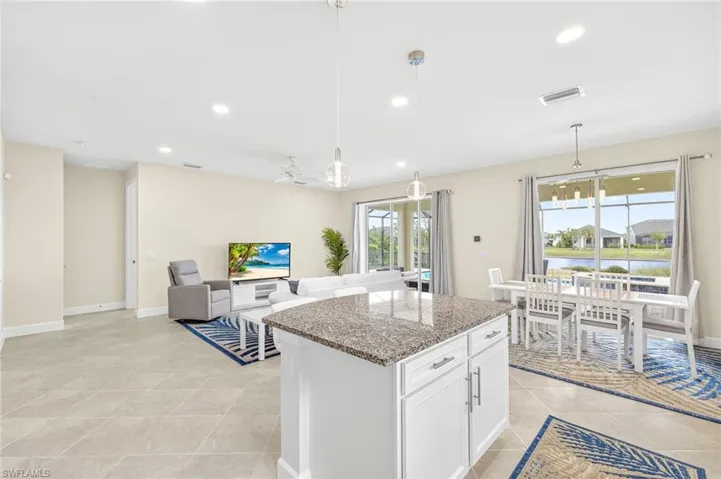 Kitchen with light stone counters, a kitchen island, light tile patterned floors, recessed lighting, and white cabinets