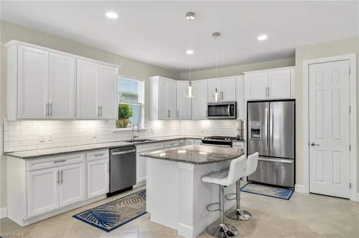 Kitchen with stainless steel appliances, dark stone counters, white cabinets, backsplash, and recessed lighting