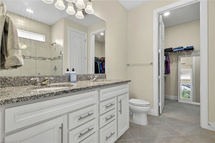 Full bathroom with double vanity, a stall shower, a spacious closet, and tile patterned flooring
