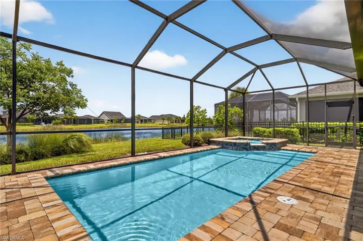 View of pool with a water view, a pool with connected hot tub, a patio, and glass enclosure