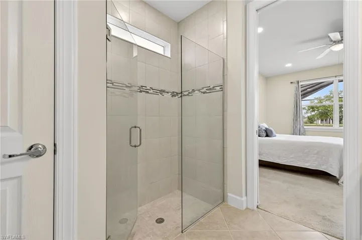 Bathroom featuring connected bathroom, a shower stall, ceiling fan, and tile patterned flooring