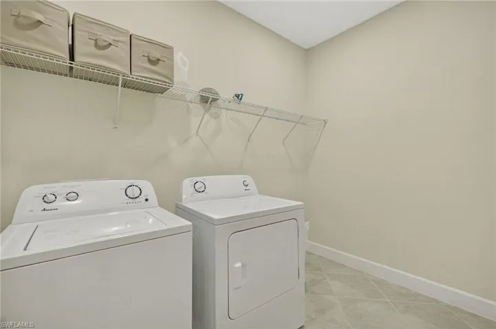 Laundry room featuring washer and dryer and light tile patterned flooring