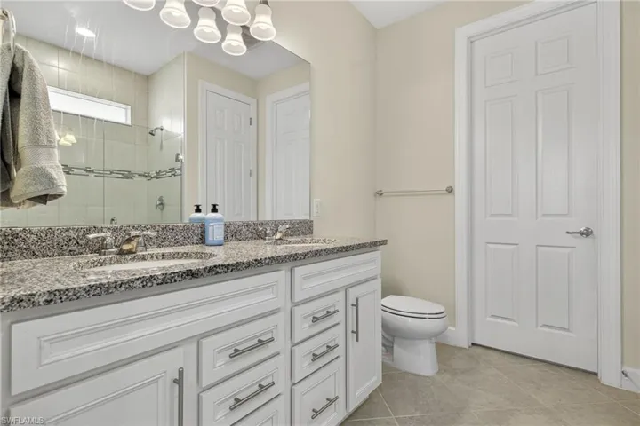 Bathroom featuring double vanity, a stall shower, and tile patterned flooring