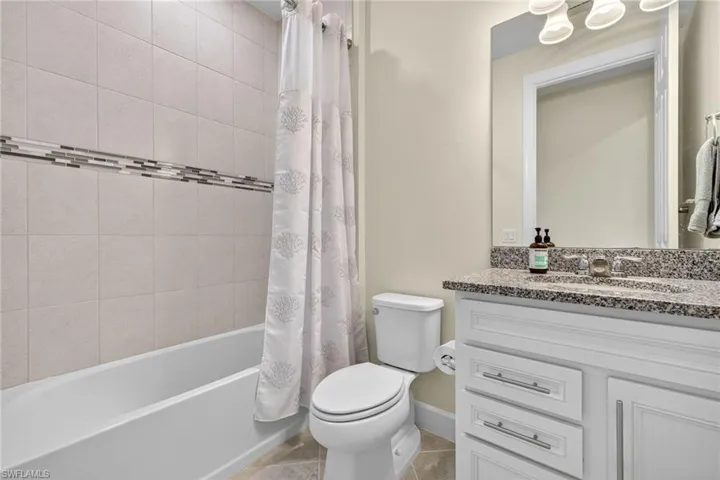 Bathroom with vanity, shower / tub combo with curtain, and tile patterned flooring