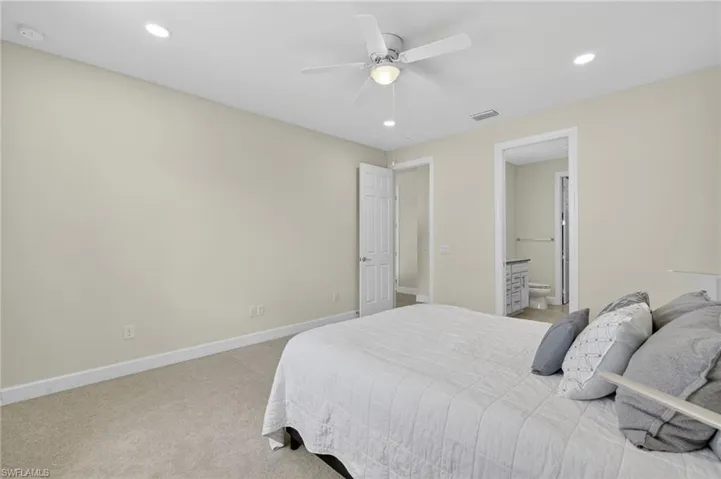 Bedroom with light colored carpet, recessed lighting, ensuite bath, and a ceiling fan