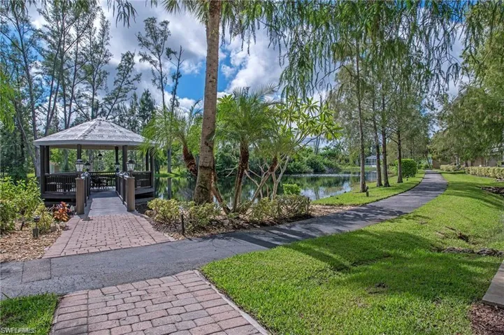Surrounding community with a water view, a gazebo, and a lawn