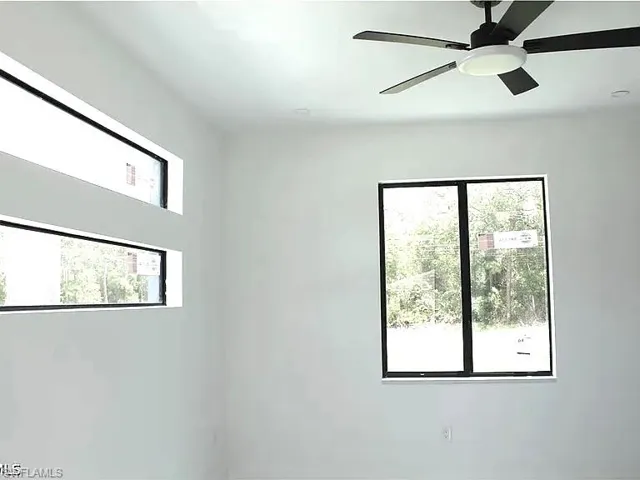 Contemporary interior with white walls, a modern ceiling fan, and multiple windows featuring black frames