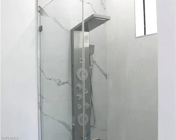 Glass-enclosed shower featuring a multi-function shower panel with rain shower head and body jets