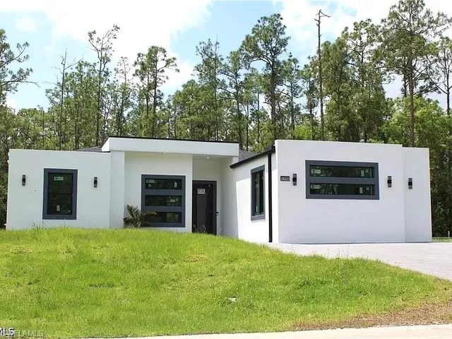 Modern architecture featuring a white stucco exterior, contrasting dark-framed windows, and contemporary outdoor sconces