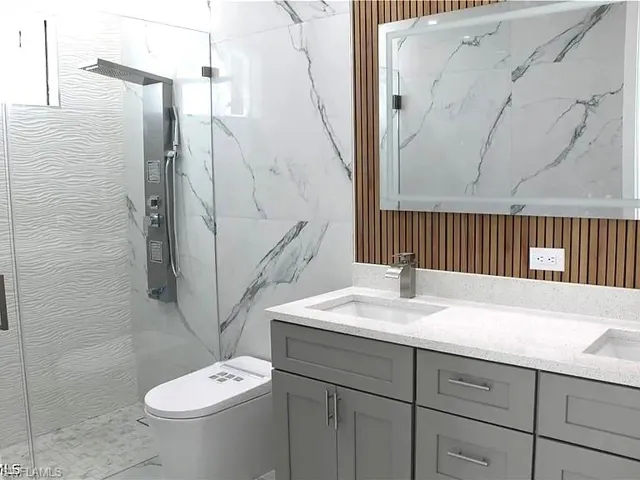 Contemporary bathroom featuring a dual vanity with light gray cabinetry, white speckled countertops, and undermount sinks