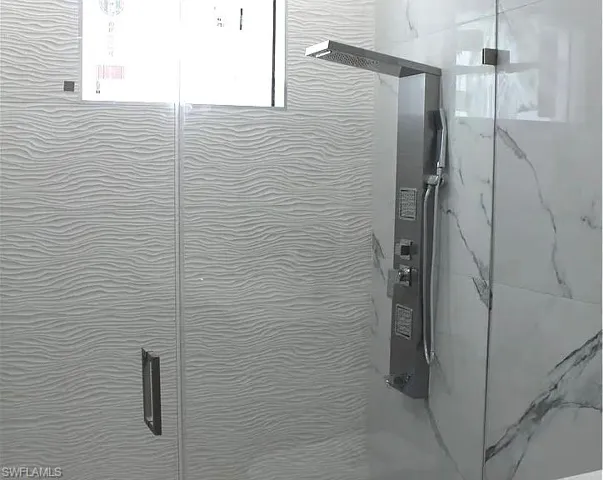 Contemporary shower featuring a multi-function shower panel with a rain shower head, handheld sprayer, and body jets