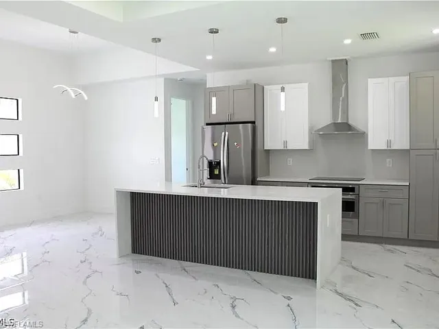 Gourmet kitchen with a waterfall island, integrated sink, and stainless steel appliances