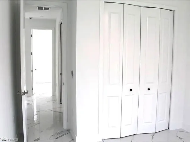 White paneled bi-fold closet doors featuring matte black hardware, set against a backdrop of white walls
