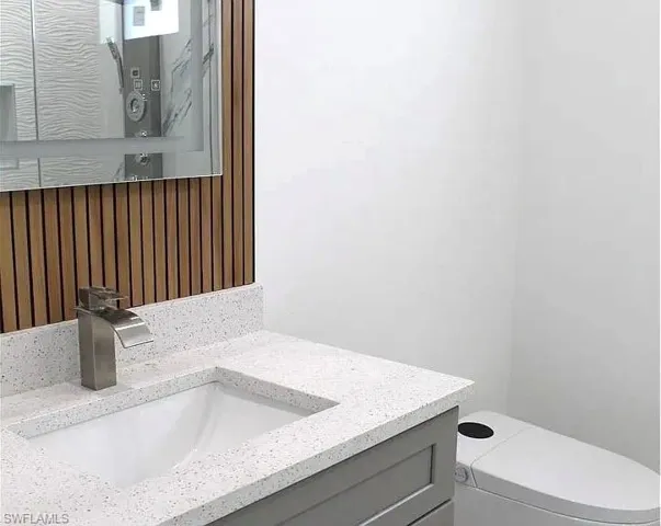 Contemporary bathroom vanity featuring a speckled white countertop, integrated rectangular sink, and brushed nickel faucet