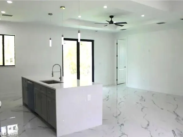 Kitchen island featuring a single-basin sink with a gooseneck faucet, light gray cabinetry, and a light-toned countertop