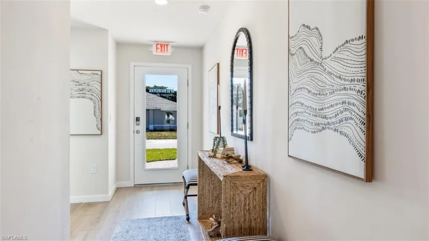 Model home. Doorway to outside featuring wood finished floors and baseboards