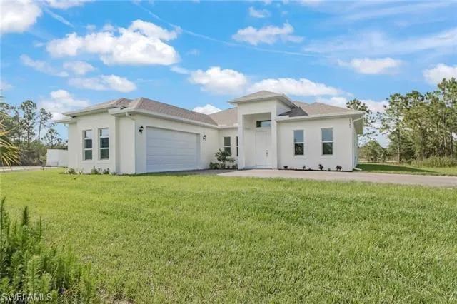 View of front of property featuring a garage and a front lawn
