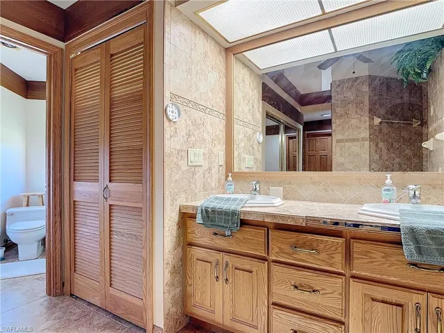 Full bathroom with a closet, a sink, tile walls, and toilet