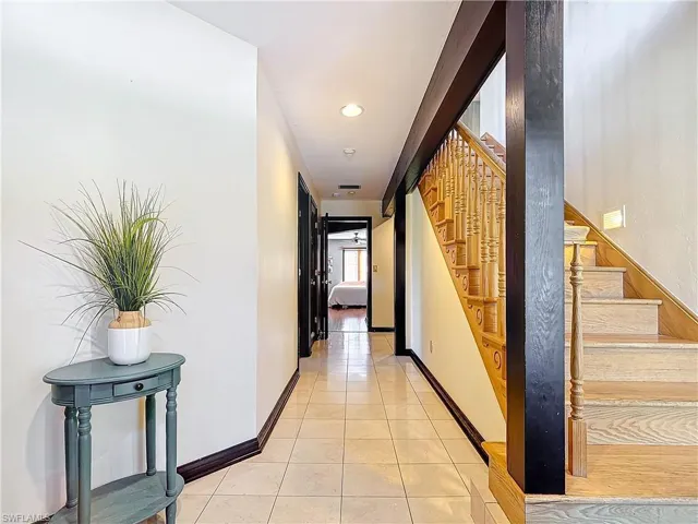 Hallway with baseboards, stairway, and light tile patterned flooring