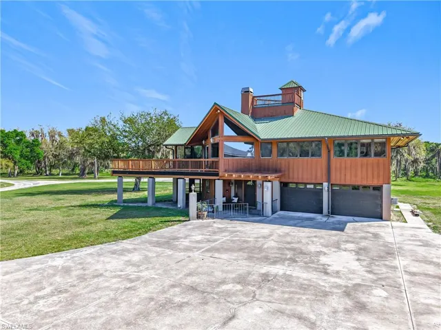 View of front of home featuring a garage, driveway, a chimney, metal roof, and a front lawn