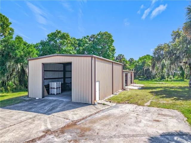 View of pole building with concrete driveway and a yard