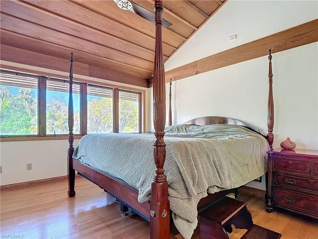 Bedroom with wood ceiling, baseboards, vaulted ceiling, and wood finished floors