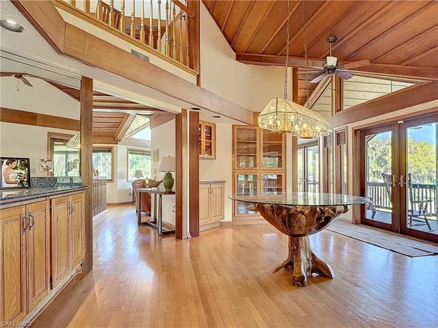 Dining area with high vaulted ceiling, a ceiling fan, wood ceiling, light wood-style floors, and french doors