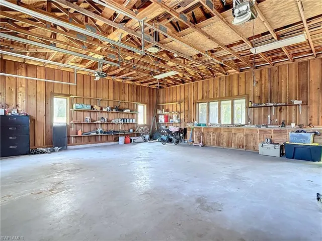 Garage with wooden walls, a workshop area, and a garage door opener