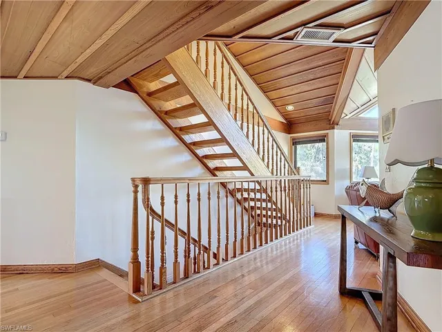 Staircase with lofted ceiling, wood-type flooring, wooden ceiling, and baseboards