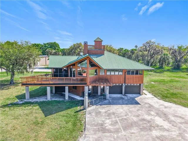 View of front facade featuring a garage, driveway, a front lawn, and metal roof