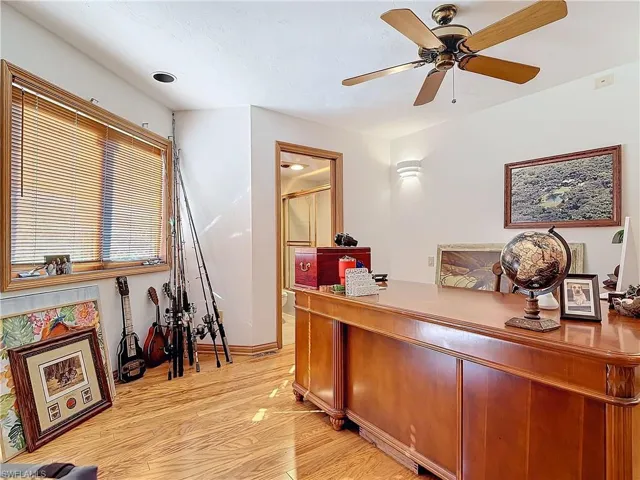 Office area with light wood-style floors and ceiling fan