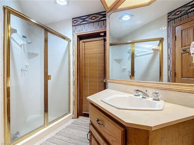 Bathroom with a stall shower, vanity, and recessed lighting