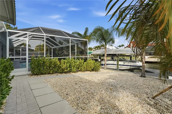 View of yard featuring glass enclosure, a sunroom, and a water view