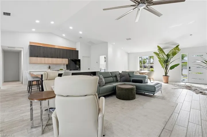 Living room with wood finish floors, a ceiling fan, recessed lighting, and a high ceiling
