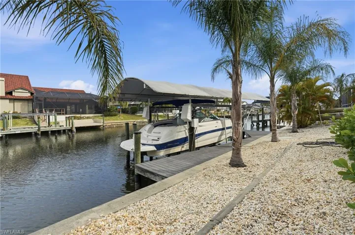 Dock area featuring boat lift, a water view, and a sunroom