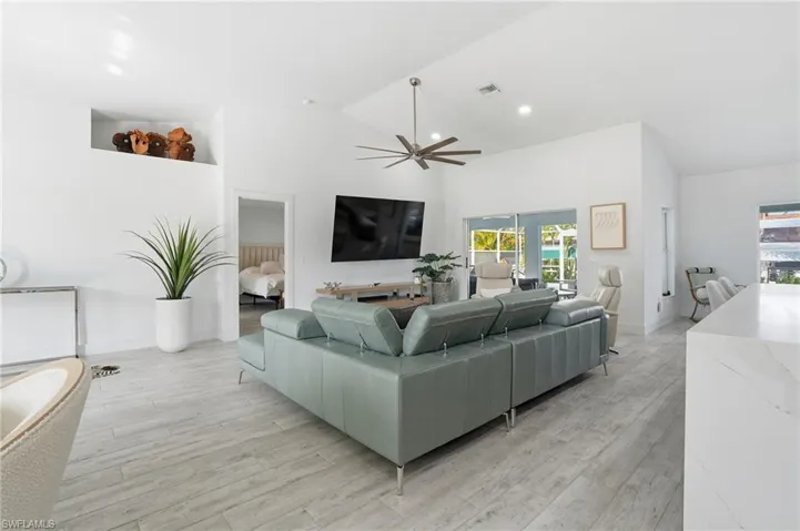 Living room featuring light wood-style floors, ceiling fan, and lofted ceiling