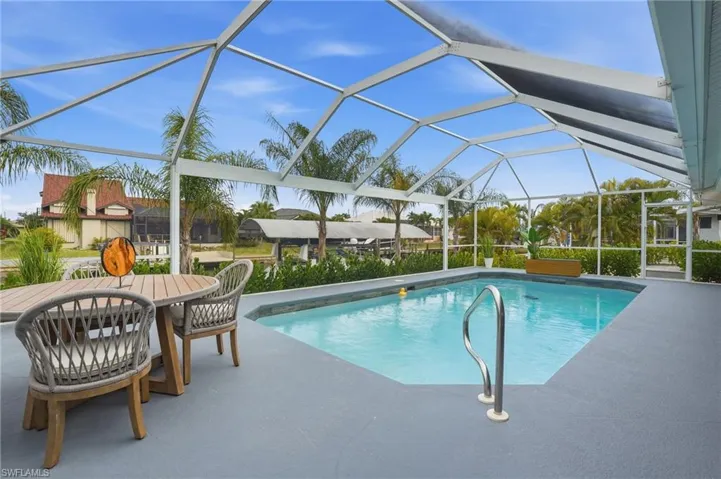 Outdoor pool featuring glass enclosure, a patio area, a sunroom, and outdoor dining space