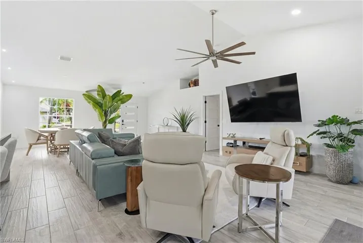 Living area featuring lofted ceiling, wood tiled floors, ceiling fan, and recessed lighting