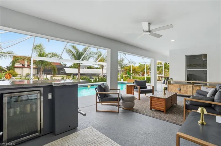 View of patio featuring an outdoor living space, a sunroom, glass enclosure, an outdoor pool, and wine cooler