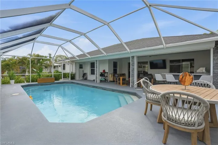 Swimming pool featuring outdoor dining space, a sunroom, glass enclosure, and a patio