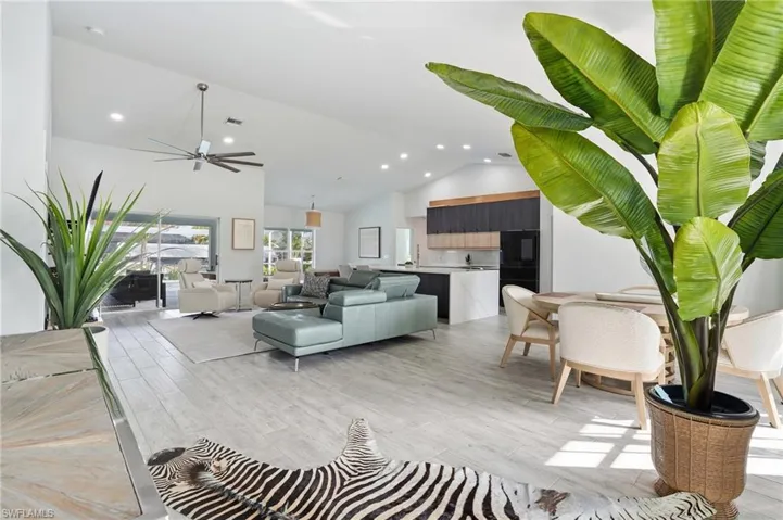 Living room with ceiling fan, vaulted ceiling, light wood finished floors, and recessed lighting
