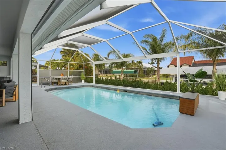 View of pool featuring a sunroom, patio surround, glass enclosure, and outdoor dining area