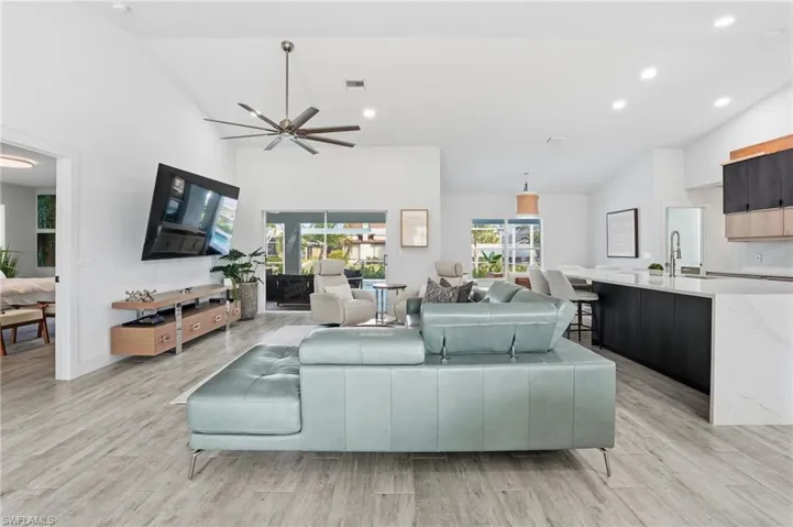 Living room featuring vaulted ceiling, light wood-style floors, ceiling fan, and recessed lighting