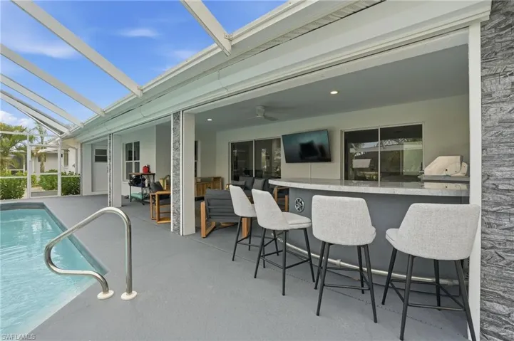 Outdoor pool featuring a sunroom, glass enclosure, a patio area, and area for grilling