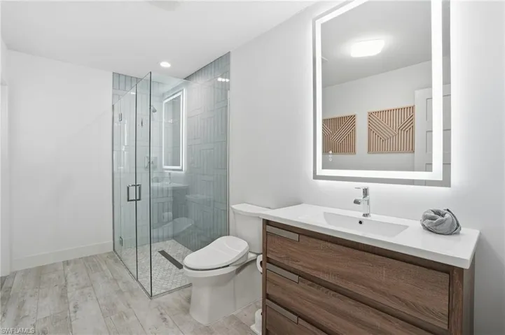 Full bathroom featuring vanity, light wood-style flooring, a shower stall, and recessed lighting