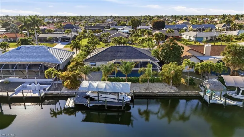 Dock featuring boat lift, a water view, glass enclosure, and a residential view