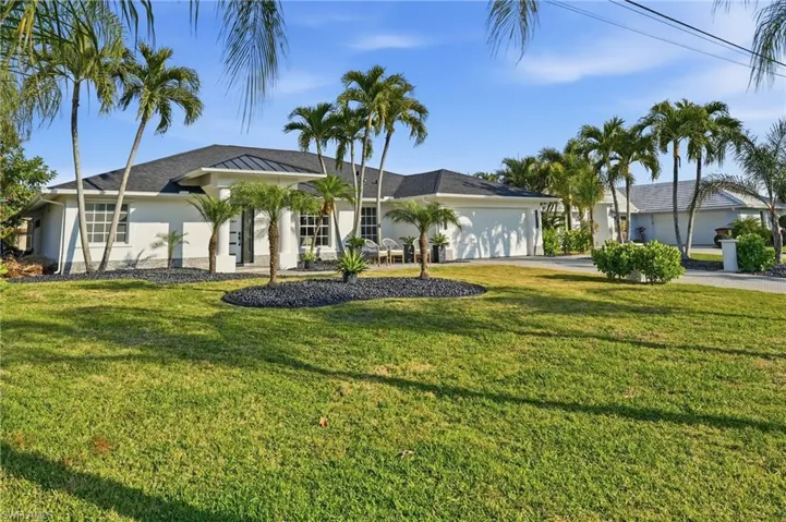 Single story home featuring an attached garage, driveway, stucco siding, and a front yard